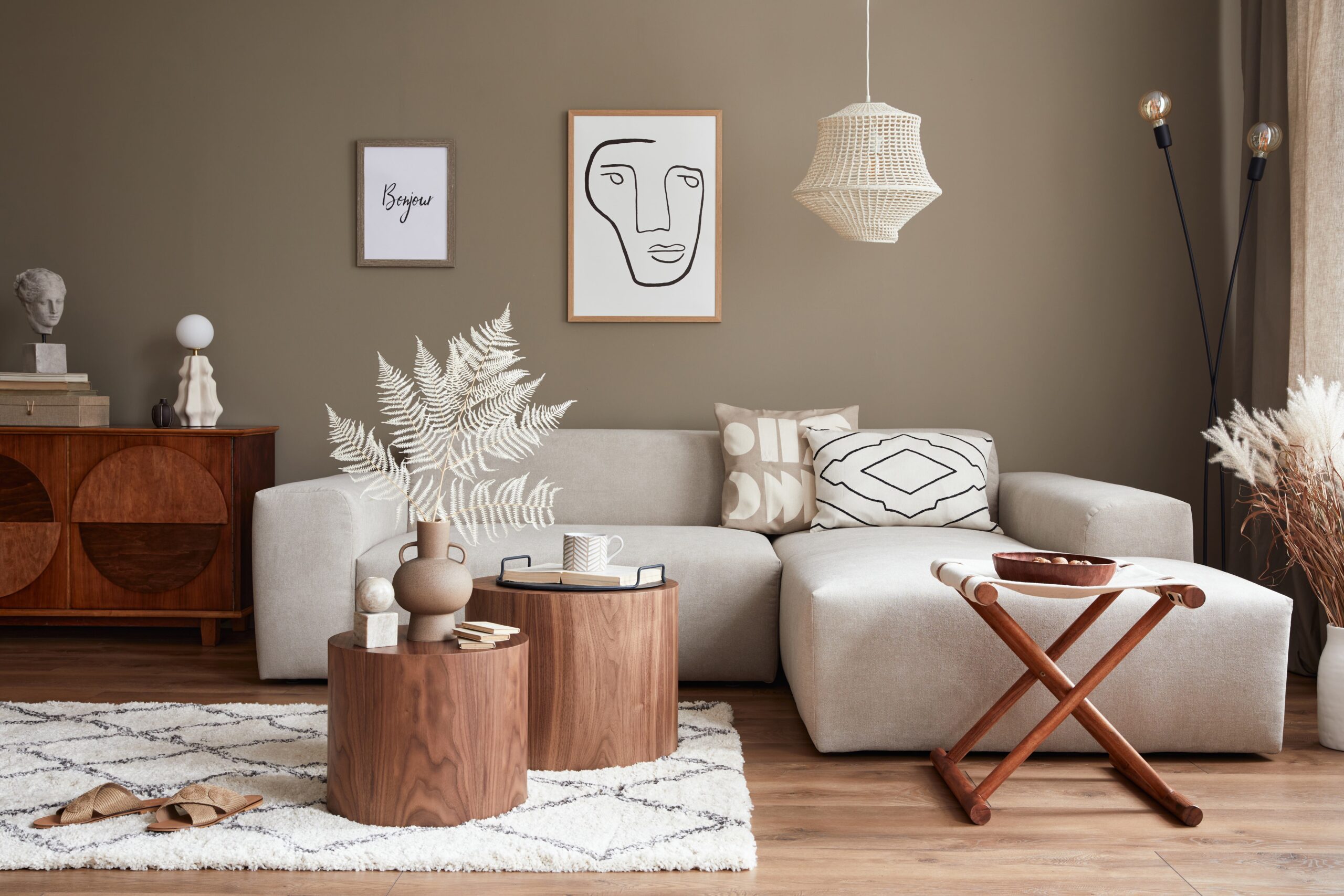 Interior design of stylish living room with modern neutral sofa, mock up poster farmes, dried flowers in vase, coffee tables, decoration and elegant personal accessories in home decor. Template.