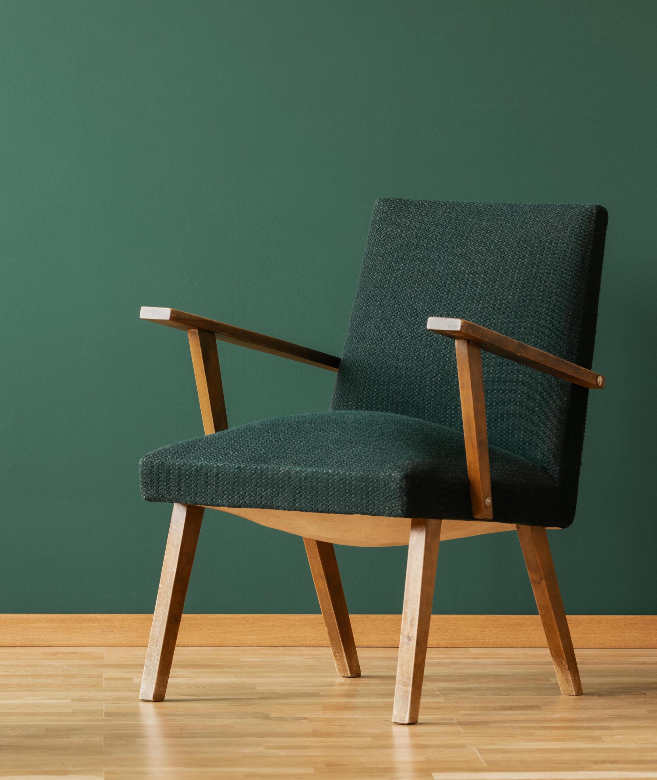 Wooden armchair next to table with leaf and book in green and blue living room interior. Real photo